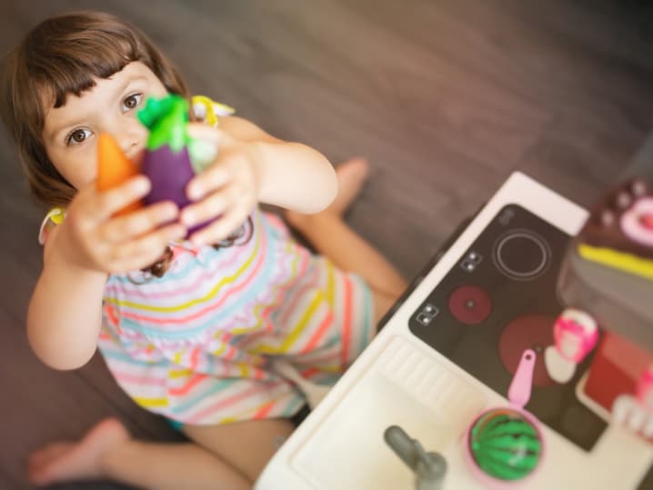 little girl playing with kitchen set