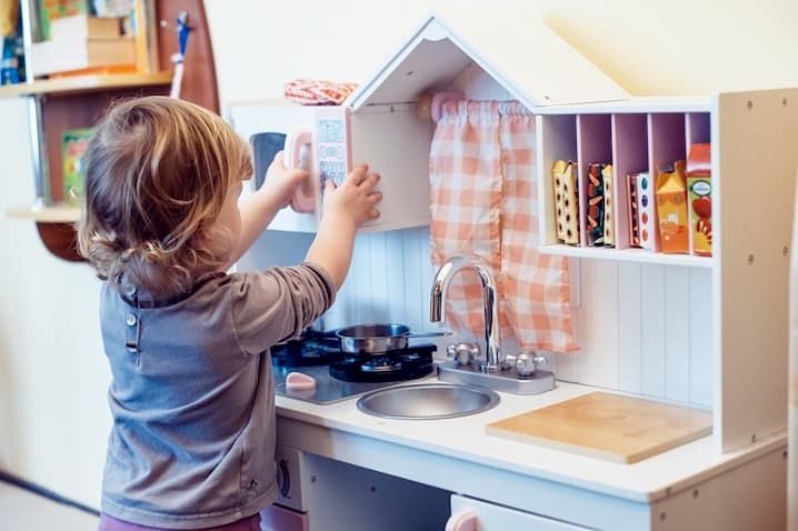 toddler playing pretend kitchen