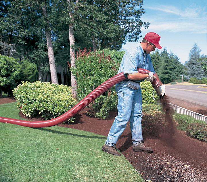 man blowing brown mulch