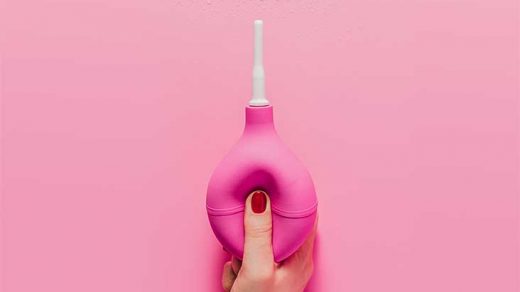 cropped shot of woman holding douche on pink