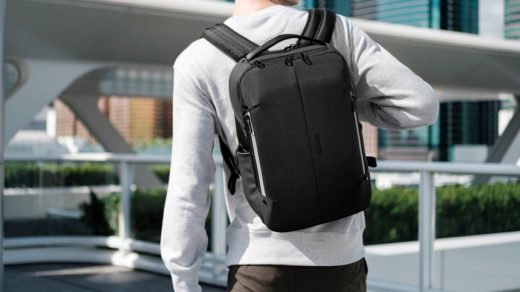 Man standing and showing his black backpack