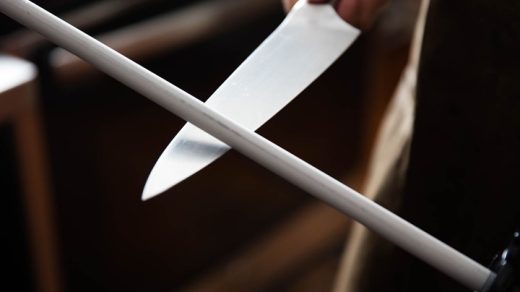 person sharpening a knife on a sharpening rod