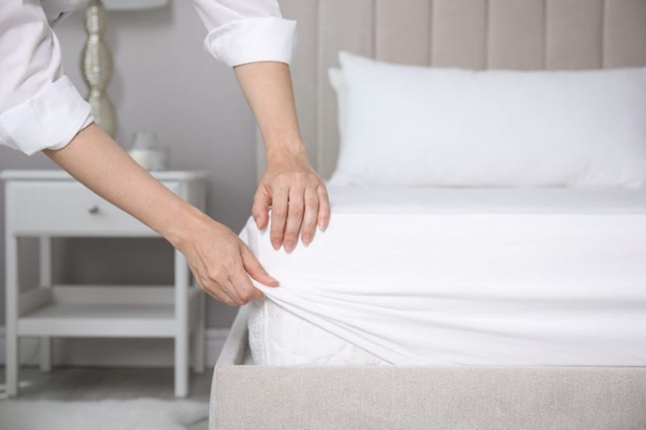 A woman is putting a cover on the mattress