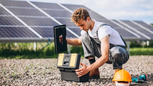 Man worker in the field by the solar panels